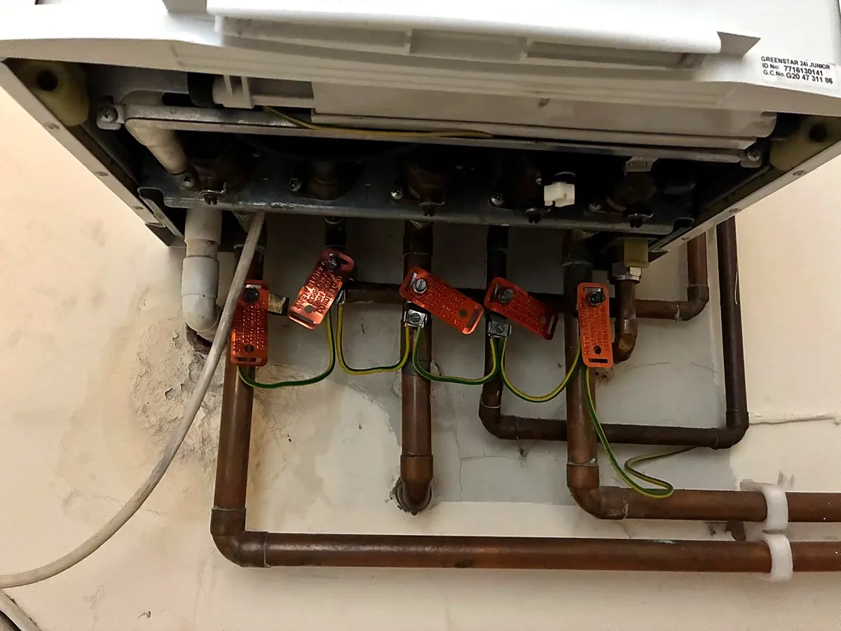 Boiler pipework with earth bonding clamps checked during a gas safety inspection