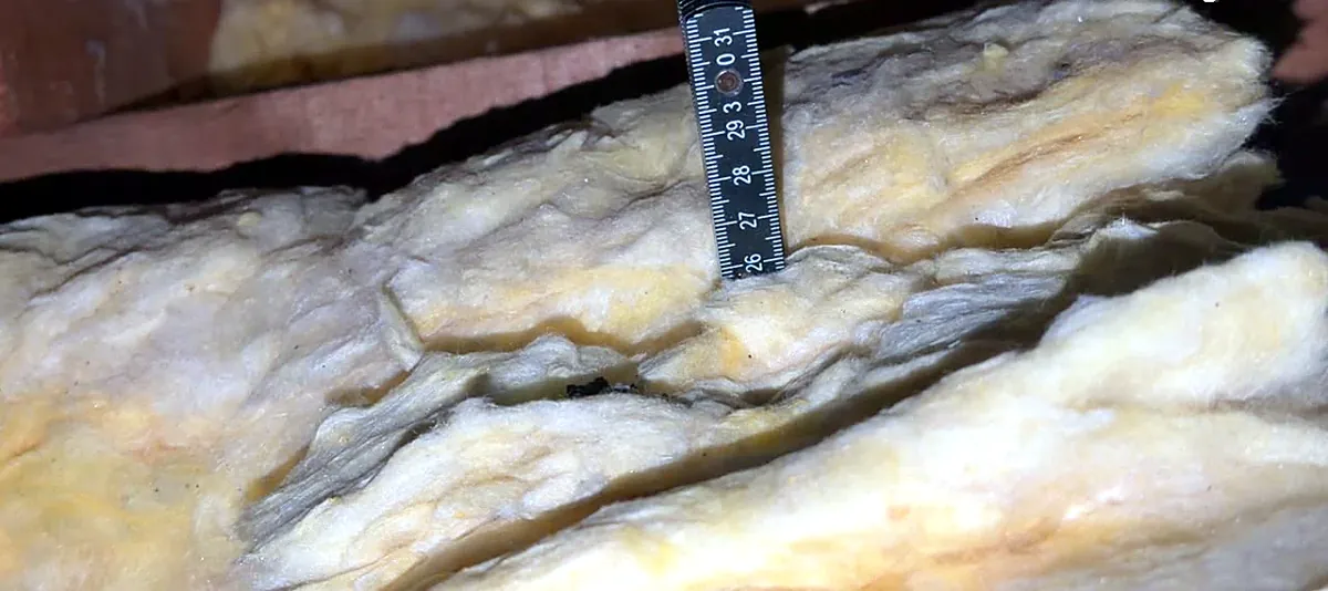 Measuring loft insulation depth with a ruler during an EPC in Luton