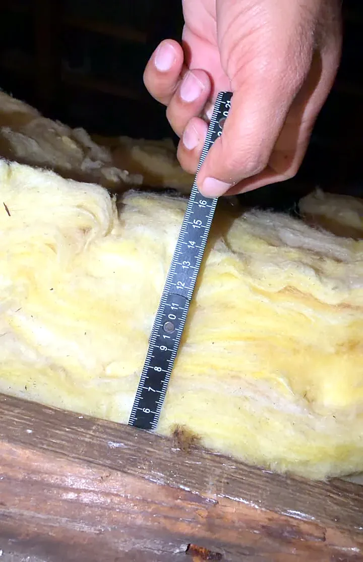 Energy assessor measuring thin loft insulation, a common reason for a lower EPC rating