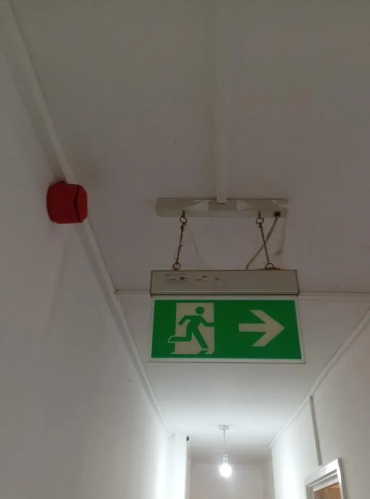 Illuminated fire exit sign and alarm sounder in a corridor