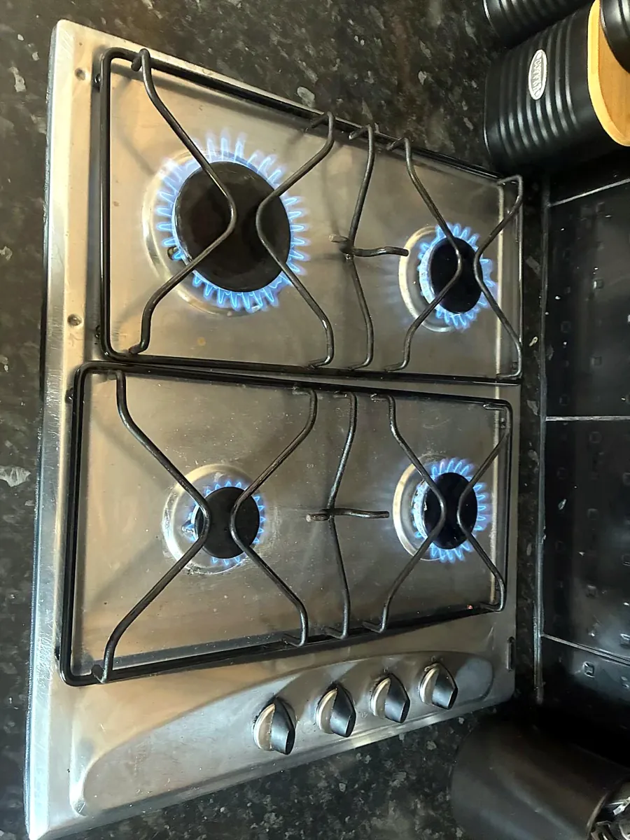 Gas hob burners lit with even blue flames during an appliance safety check