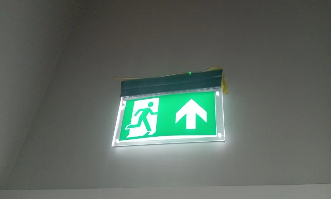 Illuminated emergency exit sign above an escape route