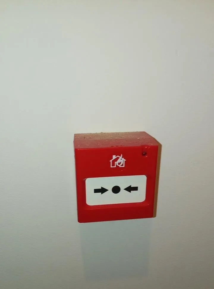 Red manual call point on a wall, part of the building's fire alarm